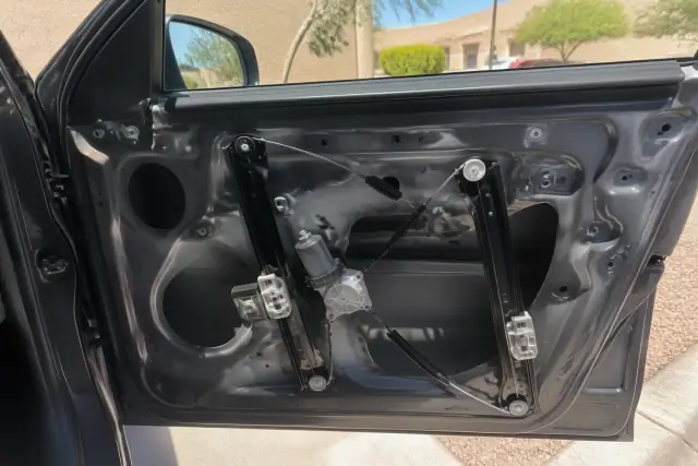 Window regulator assembly inside a car door during a repair in Tempe, AZ.