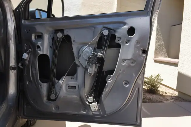A vehicle door with the interior panel removed, showing a window regulator repair in progress in Goodyear, AZ.