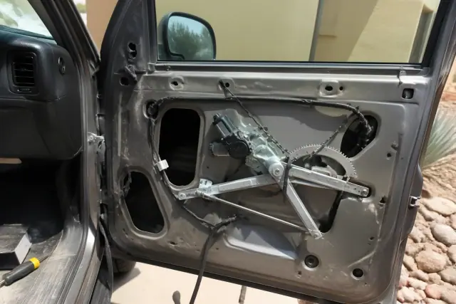 Vehicle door with the interior trim removed to show a window regulator and motor in Gilbert, AZ.