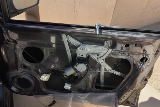 A car door with the interior panel removed, showing a window regulator repair in progress in Phoenix, AZ.
