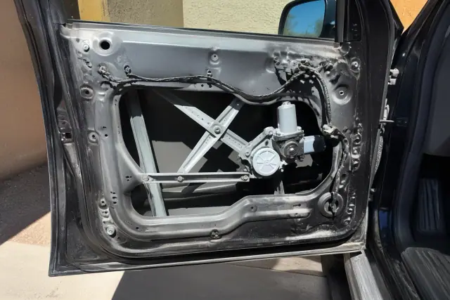A vehicle door with the interior trim panel removed, showing the window regulator and motor in Phoenix, AZ.