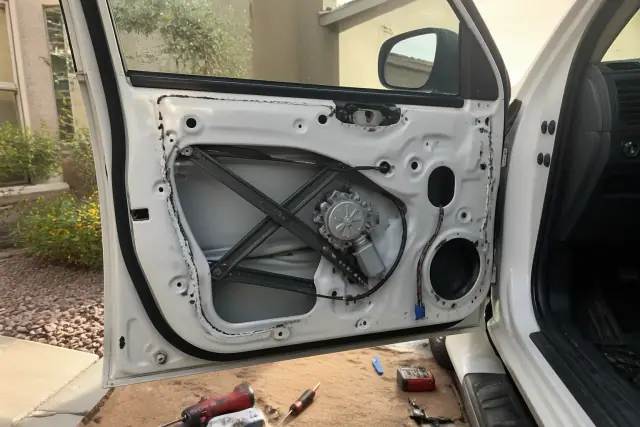 A vehicle door with the interior panel removed to show a window regulator repair in progress in Avondale, AZ.