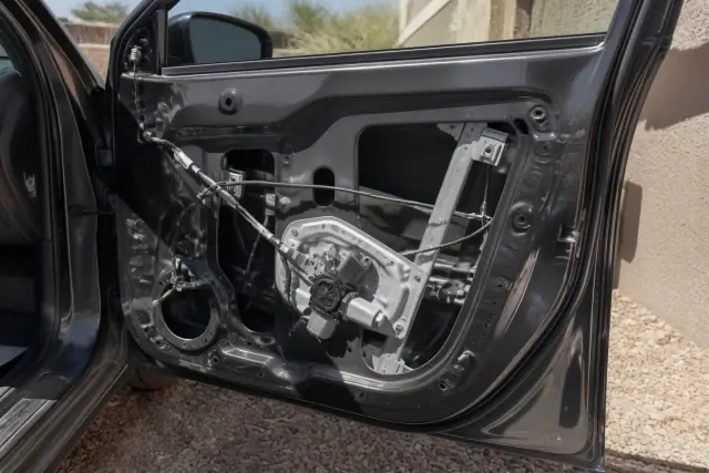 Internal car door showing a window regulator assembly and electric motor during a repair in Chandler, AZ.