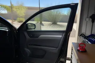Vehicle door with a new glass pane raised and a suction cup tool on a workbench in a Phoenix, AZ shop.