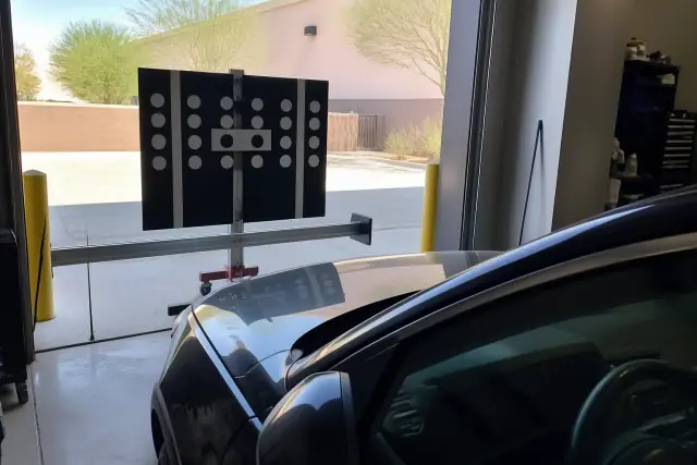 Windshield ADAS calibration target stand aligned to a vehicle in a Phoenix, AZ service bay.