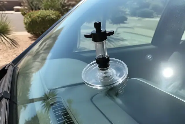 A resin injector tool repairing a star crack on a car windshield in Phoenix, AZ.