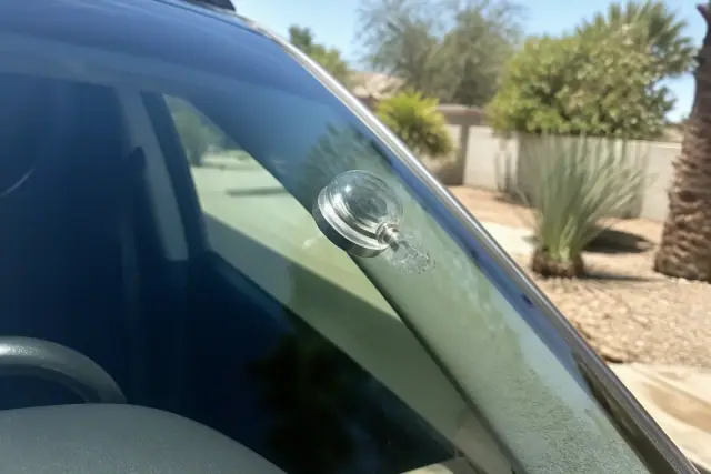 Resin injector tool repairing a windshield star break in Paradise Valley, AZ, with desert landscaping in the background.