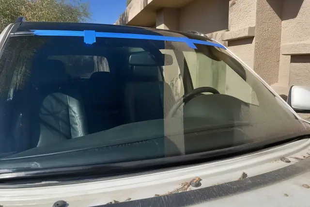 Newly installed windshield on a car with retention tape at a jobsite in Phoenix, AZ.