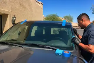 Technician performing a final windshield inspection on a car in Phoenix, AZ.