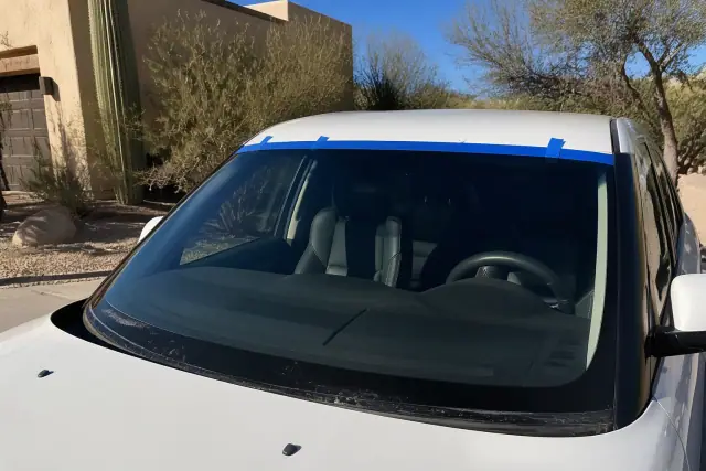 Technician installing a new windshield with retention tape on a vehicle in Scottsdale, AZ.