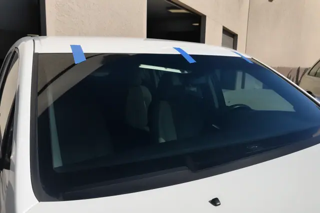 Newly installed car windshield with retention tape at a repair shop in Chandler, AZ.