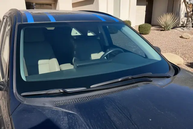 Newly installed windshield with retention tape on a vehicle in Glendale, AZ, parked in a desert landscape.