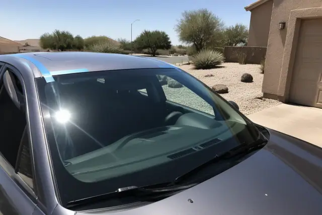 Newly installed car windshield with retention tape on a vehicle in a Phoenix, AZ desert driveway.