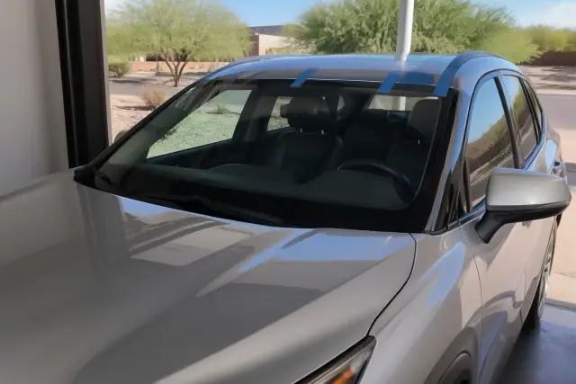 A vehicle with a newly installed windshield and retention tape parked in a Mesa, AZ service bay.