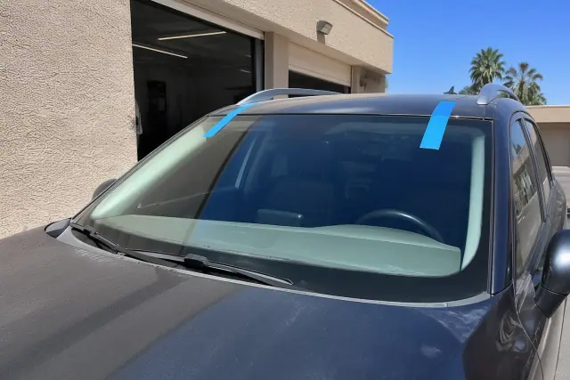 New windshield installed on a vehicle with retention tape at a service bay in Phoenix, AZ.