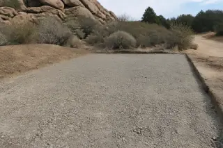 Exposed aggregate base layer prepared for new pavement near granite boulders in Prescott, AZ.