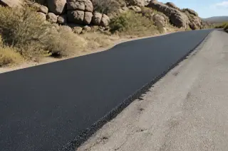 Smooth new asphalt patch next to existing pavement and granite boulders in Prescott, AZ.