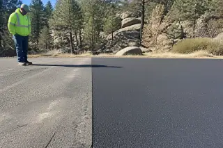 Worker inspecting a clean asphalt butt joint near granite rocks and pine trees in Prescott, AZ.