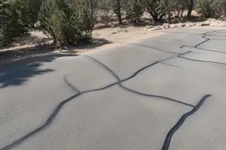 Rubberized crack sealant applied to asphalt pavement fractures near high-desert landscape in Prescott, AZ.