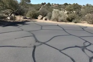 Rubberized crack sealant applied to asphalt pavement fractures in a desert landscape in Prescott, AZ.