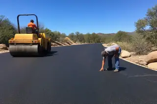 Contractor inspecting the smooth surface of a new asphalt driveway in Prescott, AZ.