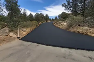 New asphalt driveway strip transitioning to old pavement in a desert landscape in Prescott, AZ.