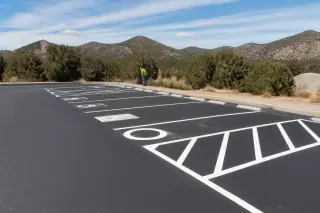Newly painted white parking lot lines on asphalt with desert scrub and mountains in Prescott, AZ.