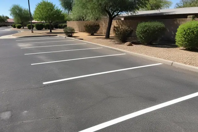 Freshly painted white parking lot lines on gray asphalt with desert landscaping in Scottsdale, AZ.
