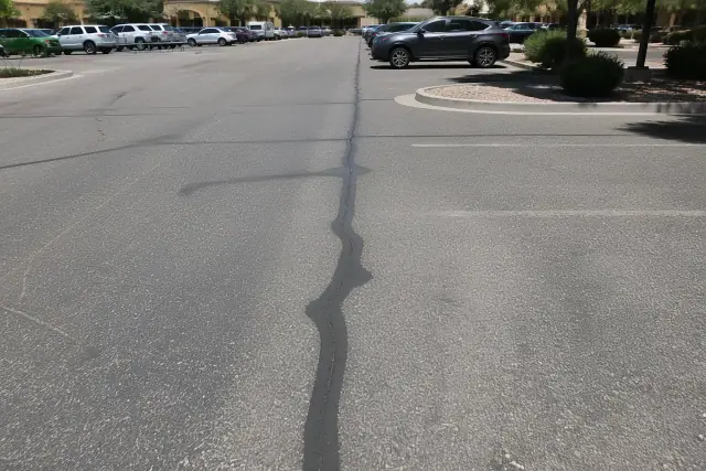 Freshly sealed crack in a parking lot pavement at a retail center in Queen Creek, AZ.