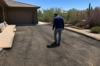 Technician inspecting a milled asphalt surface near a garage and prickly pear cactus in Scottsdale, AZ.