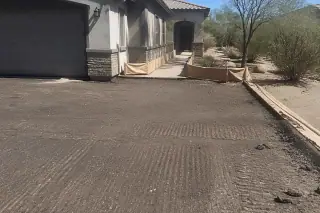 Milled asphalt surface with a granular texture beside a house and desert scrub in Scottsdale, AZ.