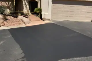 Fresh asphalt patch perfectly leveled with existing pavement by a garage in Scottsdale, AZ.