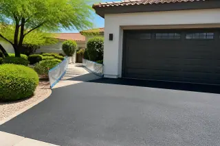 Newly repaired asphalt driveway next to a residential garage and xeriscaped yard in Scottsdale, AZ.