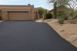 Newly surfaced dark asphalt driveway beside a residential garage and desert landscaping in Scottsdale, AZ.