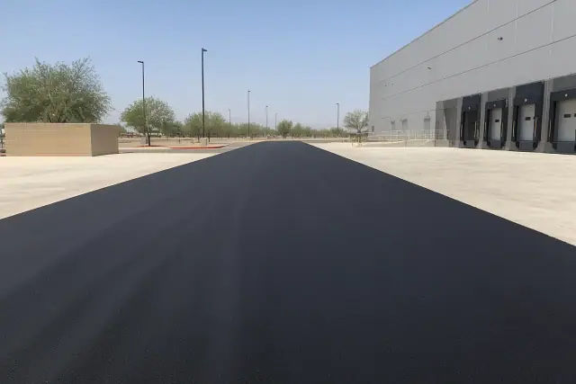 Freshly paved asphalt loading drive at a warehouse in Glendale, AZ with visible roller tracks.