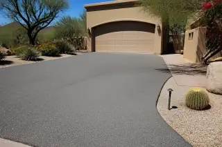 Uniform grey asphalt driveway with clean edges and desert landscaping at a home in Scottsdale, AZ.