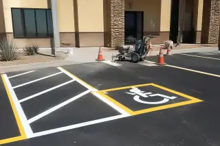Fresh white and yellow parking lot lines with a pavement symbol and safety cones in Scottsdale, AZ.