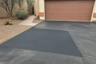 Smooth asphalt patch on a driveway next to a stucco house and desert gravel in Scottsdale, AZ.