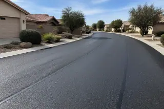 Freshly paved asphalt overlay on a residential street in Surprise, AZ, with desert landscaping and stucco homes.
