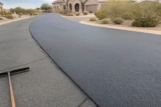 Fresh asphalt overlay with a nearby rake on a residential street in Surprise, AZ.