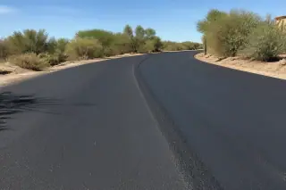 Finished asphalt overlay with sharp shadows and desert scrub in Surprise, AZ.