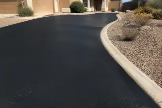 Jet-black cured sealcoating on a residential driveway next to stucco homes and desert landscaping in Surprise, AZ.