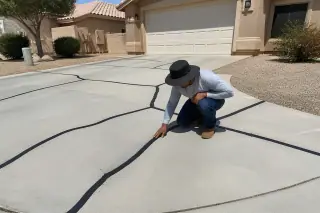Rubberized sealant filling pavement cracks on a residential driveway in Surprise, AZ.