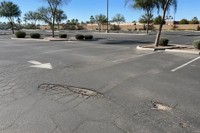 Asphalt parking lot with alligator cracking, depressions, and potholes in Tempe, AZ.