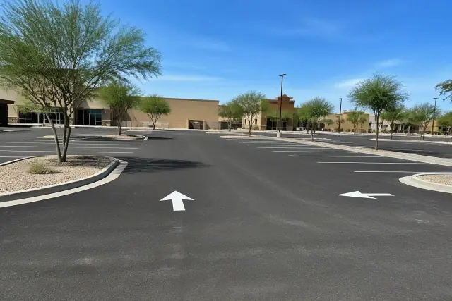 Newly paved parking lot with fresh asphalt striping and painted directional arrows at a retail center in Gilbert, AZ.
