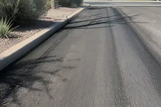 Smooth, milled asphalt texture with precise edges and sun-bleached desert xeriscaping in Tempe, AZ.