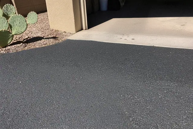 Asphalt crack filling between a garage slab and new driveway in Tempe, AZ with nearby prickly pear cactus.