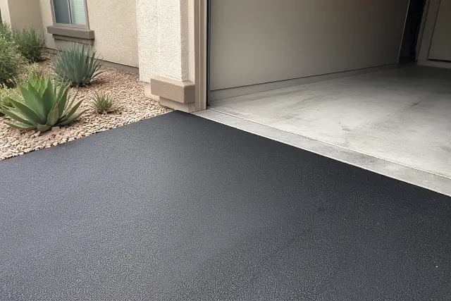 Newly installed asphalt driveway meeting a residential garage in Gilbert, AZ.