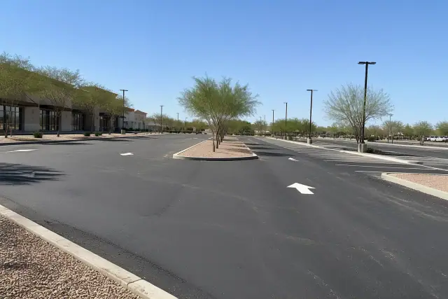 Newly paved asphalt parking lot at a retail center in Chandler, AZ with painted stall markers and desert landscaping.