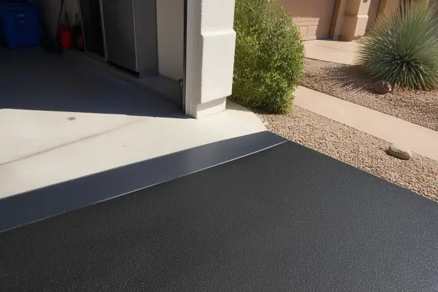 Freshly sealcoated transition between a residential garage and asphalt driveway in Mesa, AZ.